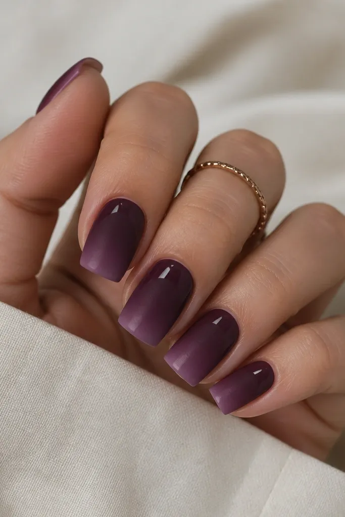 Medium square nails. The nail is dark plum ombre that fades to a lighter purple at the tips. The cuticle half looks matte, while the top third has a glossy shine, creating a two-texture gradient.