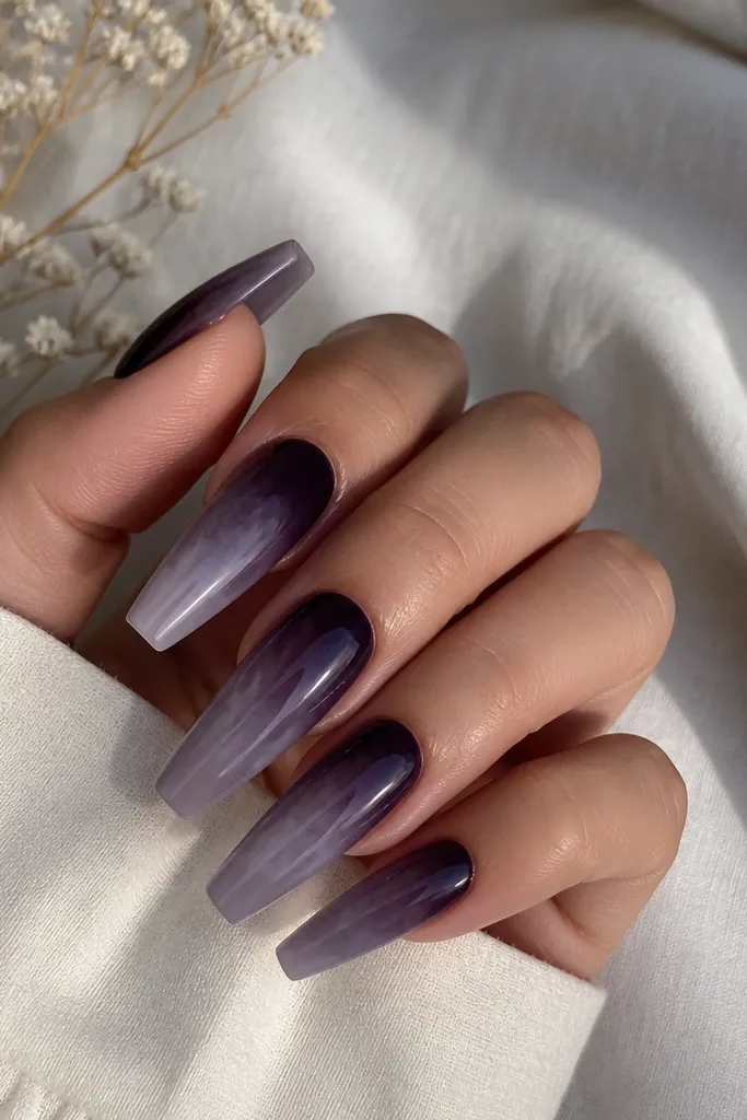 Long coffin nails. Dark purple looks smoky near the cuticle and fades into a hazier, lighter purple-gray haze toward the tips. The gradient looks like blended smoke with no sharp line.