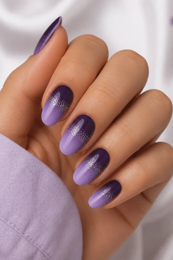 Medium oval nails. Ombre fades from dark purple at the cuticle to lighter purple at the tips, with a thin line of fine silver glitter concentrated in the middle band.