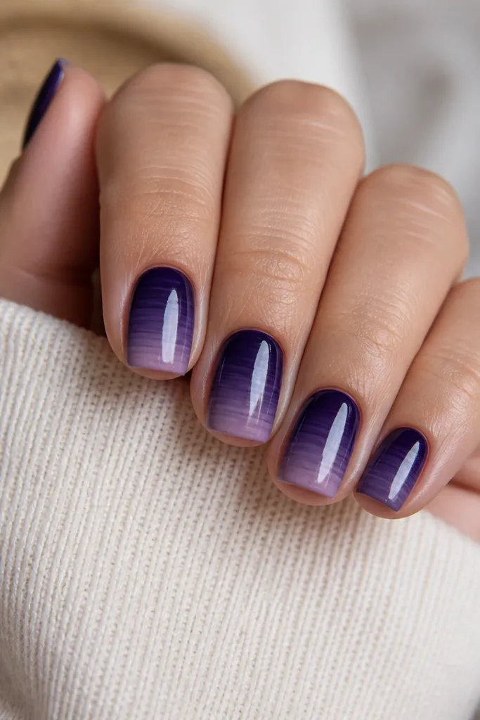 Short square nails. Dark purple ombre fades down the nail, but there are thin horizontal stripe bands where the sponge transferred in lines. The stripes are subtle and glossy.