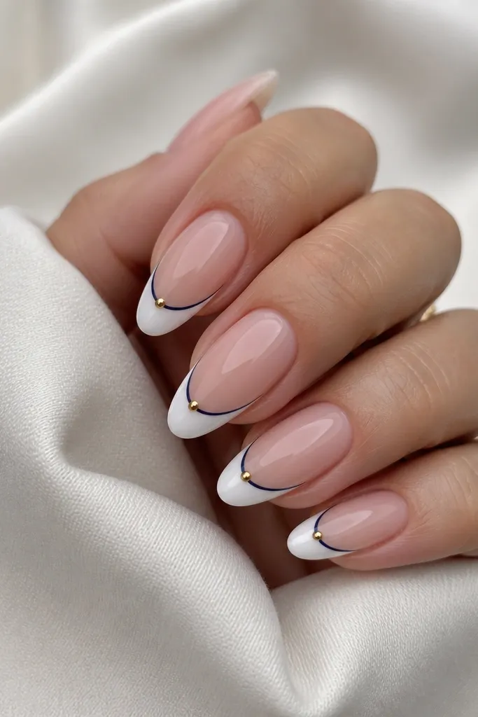 Long almond nails. Classic white tip with a thin navy outline around the smile line. A single gold dot sits at the center of the smile on each nail.