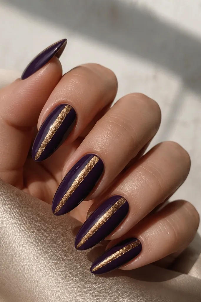 Long almond nails in deep purple with a single vertical antique gold foil stripe centered on each nail.