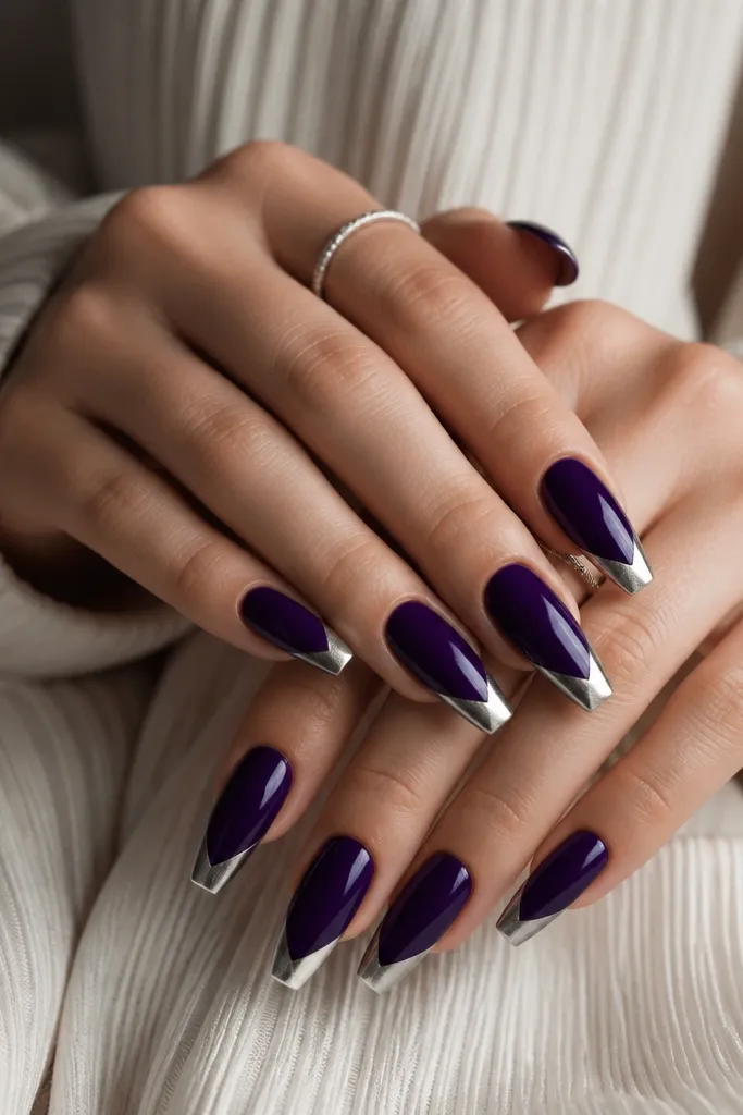 Coffin nails with solid glossy deep purple. A silver diagonal V tip cuts from both side edges toward the center tip point.