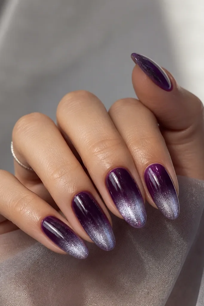 Dark purple jelly nails with a soft glow fade toward the tips. Silver shimmer creates a gradient that looks like light reflecting off glass.
