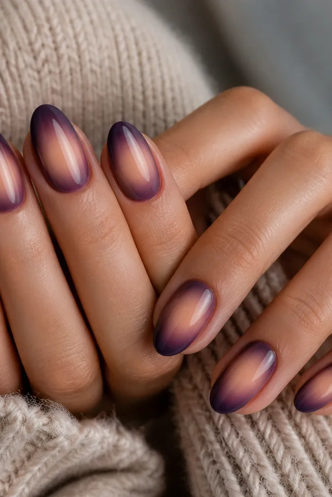 Nails with a warm beige glow in the center, surrounded by a dark purple aura fade that radiates outward. The edges blend smoothly with a soft airbrushed look.
