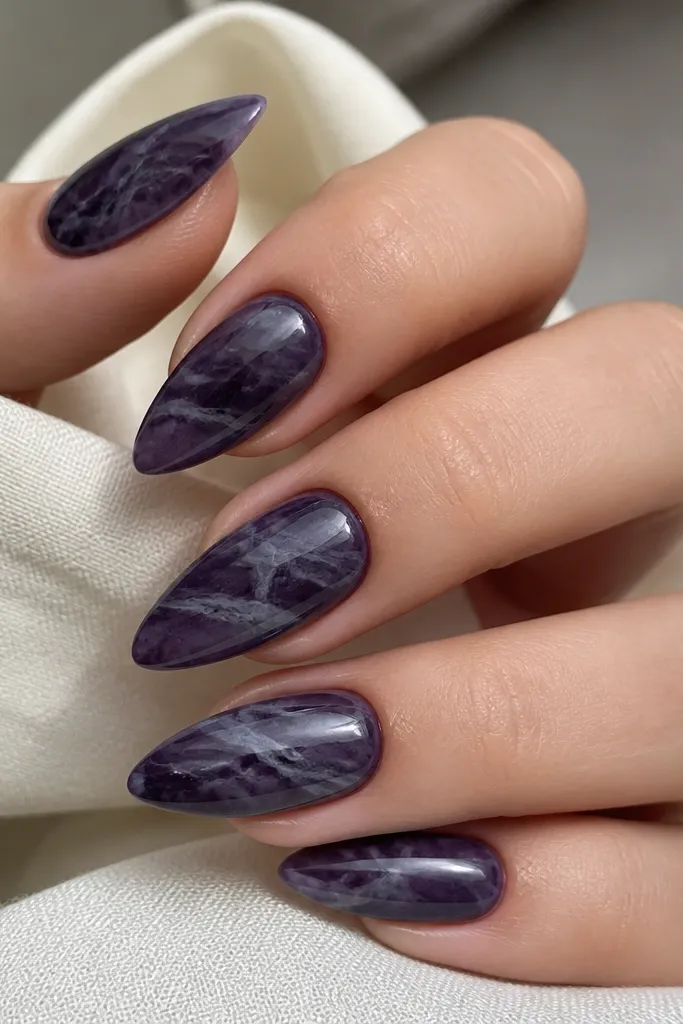 Almond nails with dark purple marble swirls. The veins look smoky and greyed, not white, and they move diagonally across each nail.