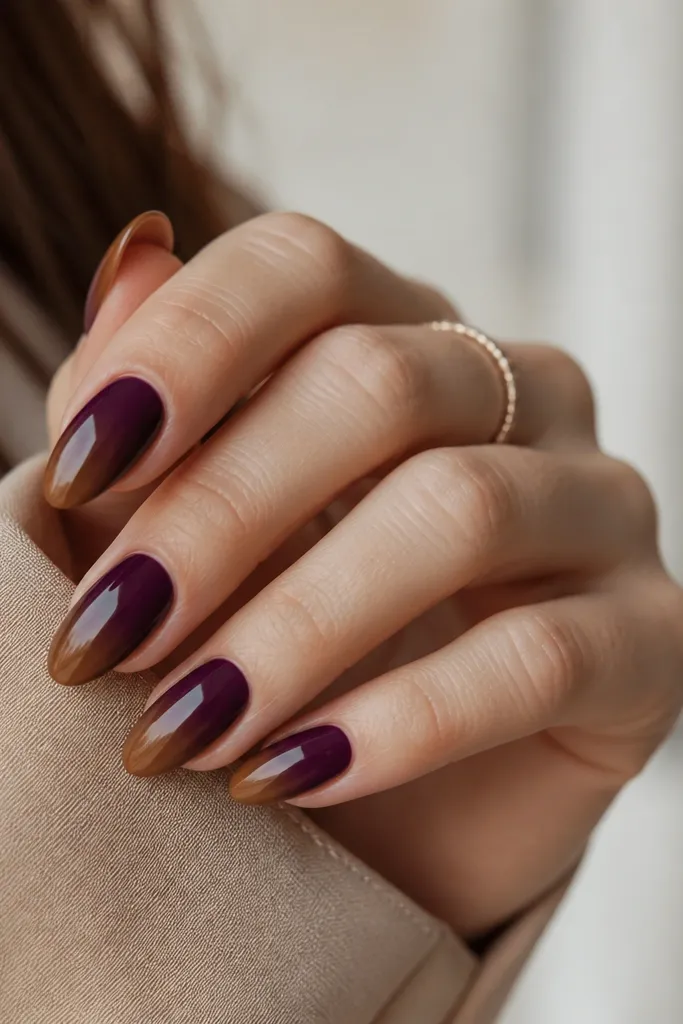 Medium almond nails with a dark purple base that fades into a chestnut brown at the tips. The ombré is smooth and looks like a natural gradient.