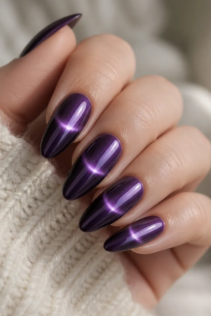 Long almond nails with a deep purple mirror chrome base. A narrow cat-eye magnetic line runs horizontally across the middle, glowing silver-violet.