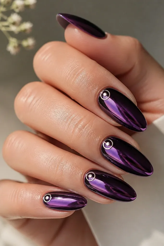 Almond nails in deep purple mirror chrome. A thin silver halo ring sits around a small central dot near the cuticle area, like a tiny crown.