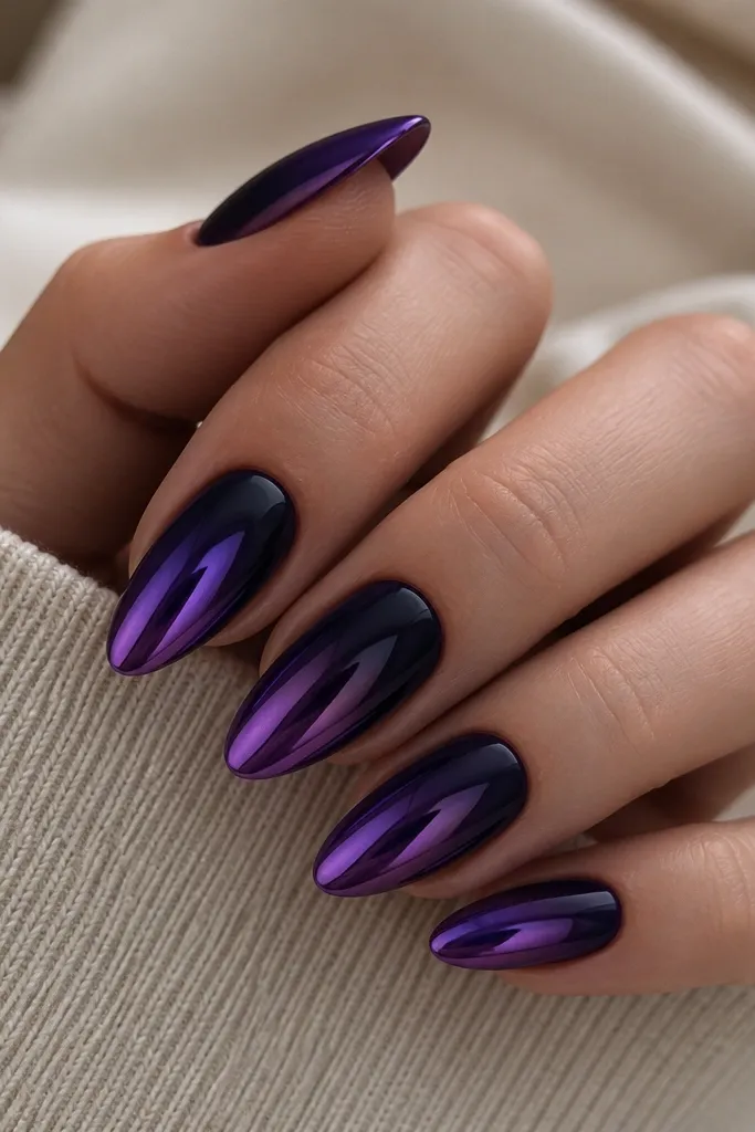 Medium almond nails with deep purple chrome concentrated on the tips. The chrome fades into a darker, more opaque violet near the cuticle, with a smooth reflective gradient.