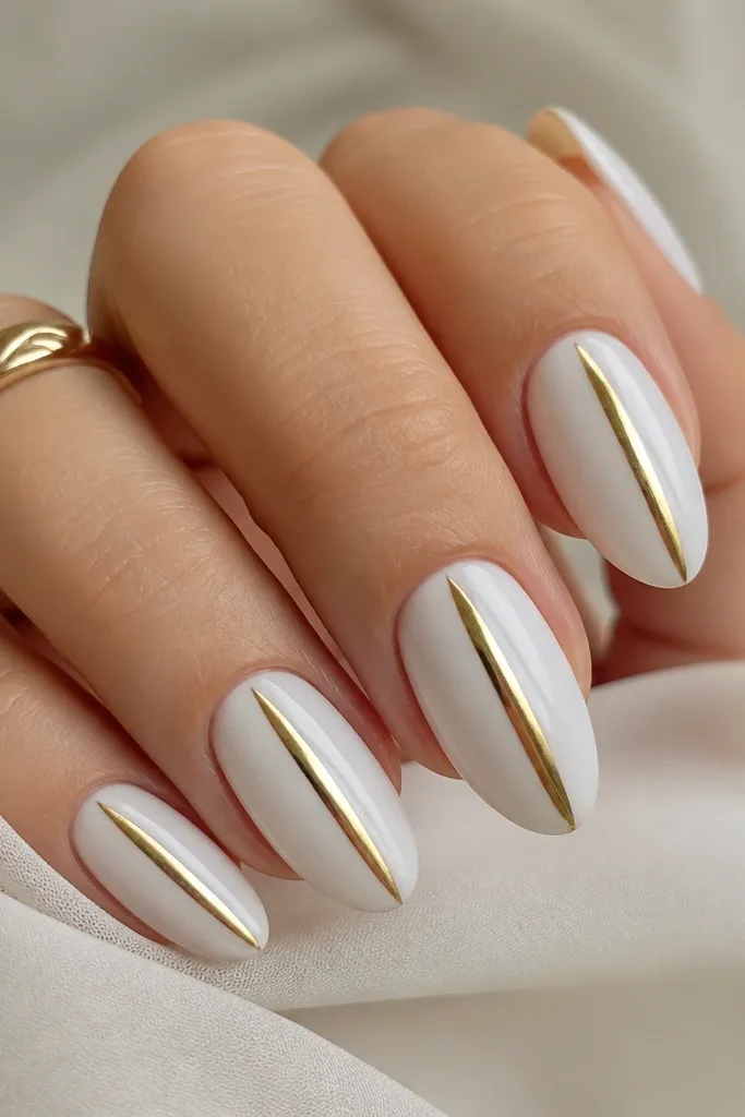 Almond nails with milky white base. A single vertical stripe of gold chrome runs from near the cuticle to the tip center. The stripe is mirror-bright with sharp edges and the rest of the nail is clean and glossy.