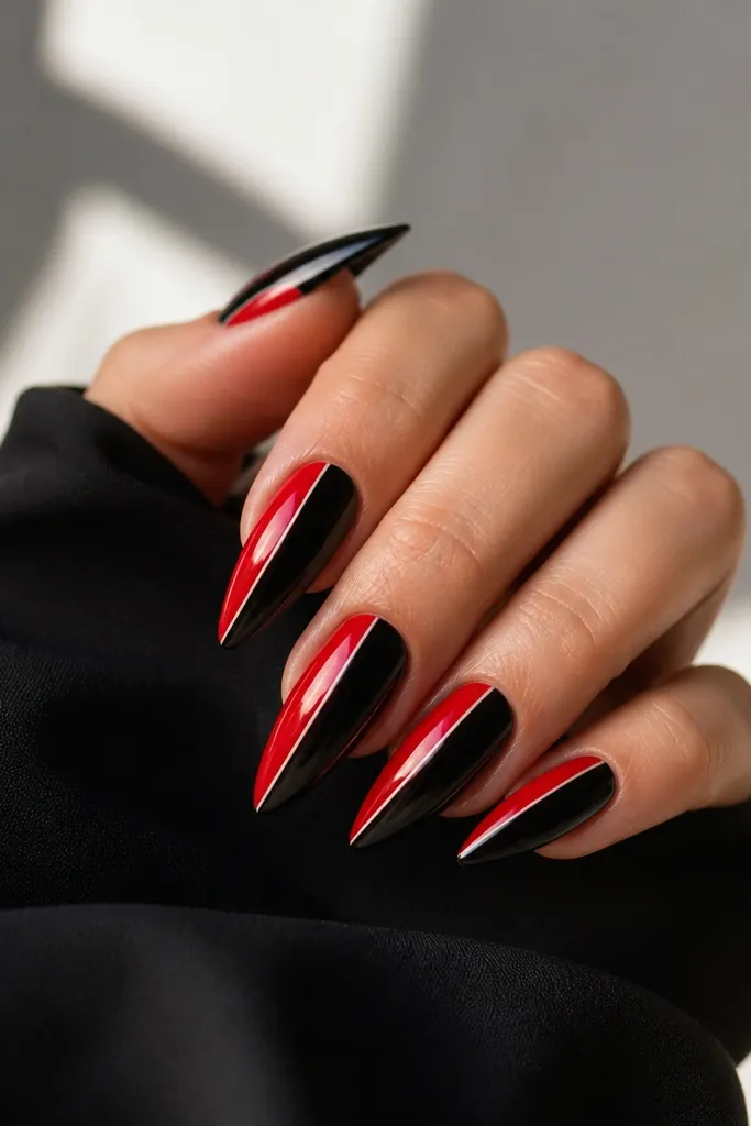 Long almond nails with a sharp diagonal split. One side is glossy red, the other glossy black. A super thin white line runs between the two colors like a separator.