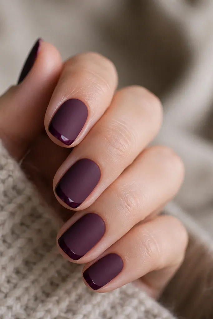 Nails are deep plum with a matte velvet finish. The very tips have a glossy line that looks like a narrow French edge, crisp and clean.