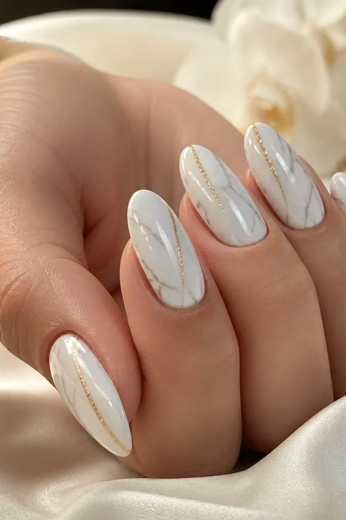 Nails painted white with thin greyish marble veins. One gold glimmer line runs diagonally from near the cuticle toward the side, with lots of shine under a glossy top coat.