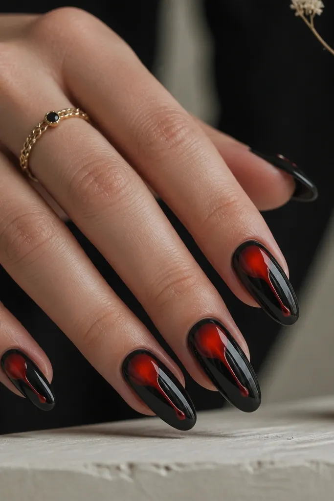 Black nails with a red aura center glow and a small red drip shape descending from the aura. Glossy top coat makes the drip look wet.