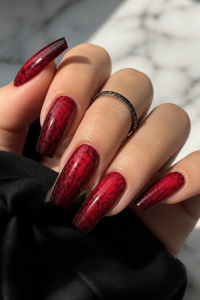 Coffin nails with a red ombre base fading from dark red at the tip into softer red near the middle; black crackle lines spiderweb across the red.