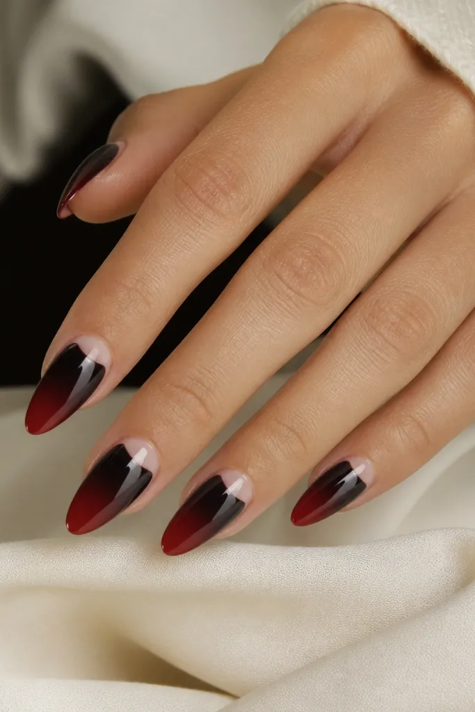 Almond nails with a clean half-moon cutout at the base; the rest of the nail has black-to-red ombre running from tip toward the center.
