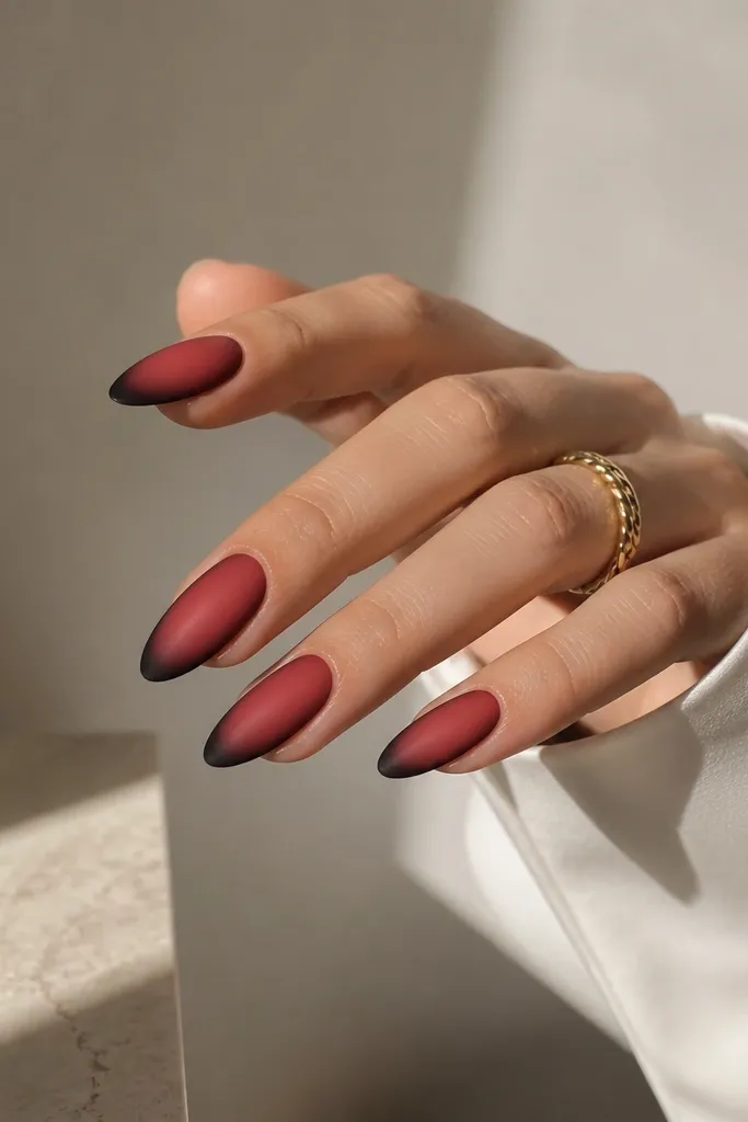 Almond nails with a satin red gradient; black forms a soft shadow at the tip like a smoky outline rather than a solid block.