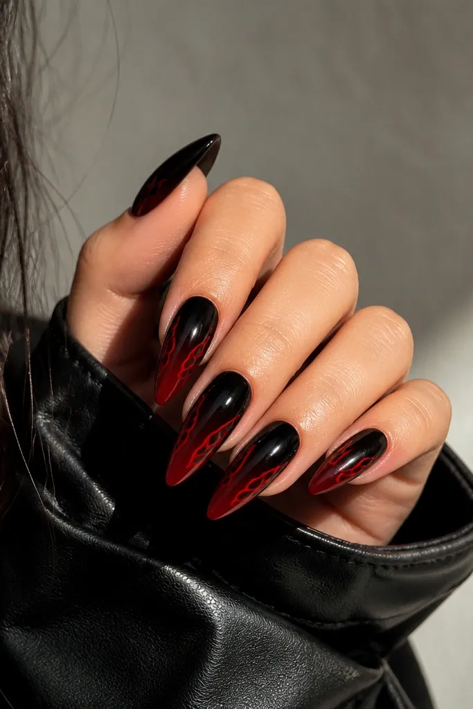 Long almond nails; black-to-red ombre with a red flame-shaped outline along the side edges, like a burning border on the gradient.