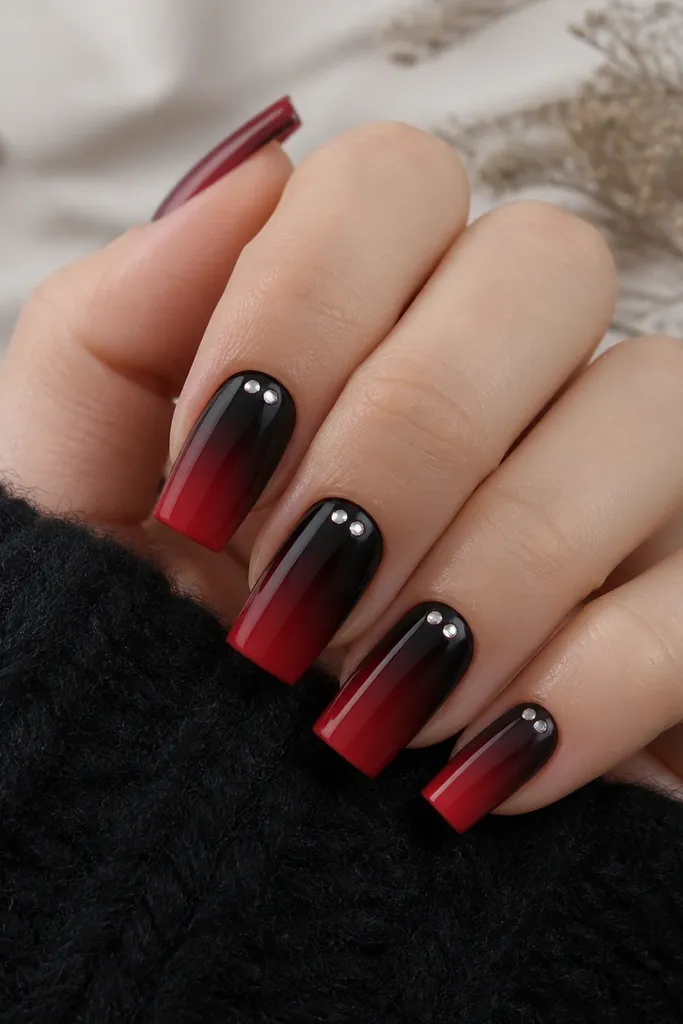 Square nails; black-to-red ombre fades smoothly; at the cuticle line there are two tiny clear crystal dots per nail, evenly spaced.