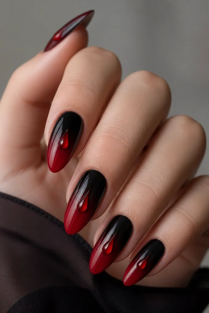 Long almond nails; black fades into red ombre with a single glossy red tear-drop highlight drawn near the center, like a droplet catching light.