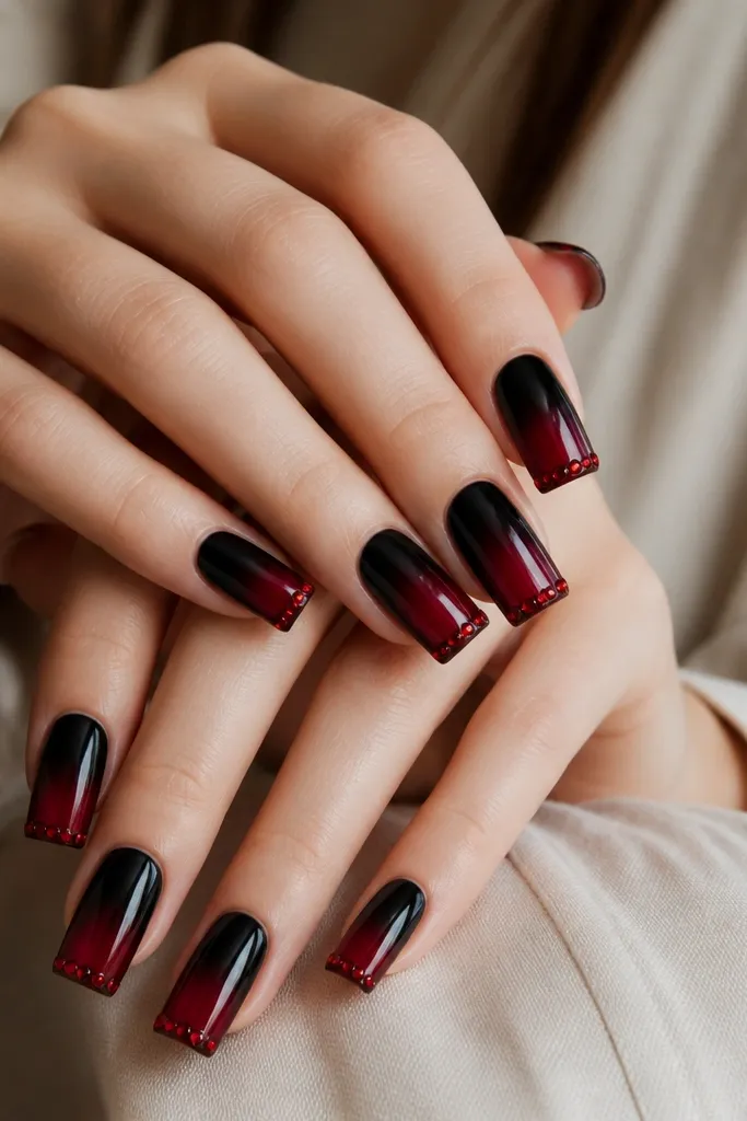 Square nails; black fades into red, and the last 2 millimeters of each nail has a line of tiny red micro studs or rhinestones.
