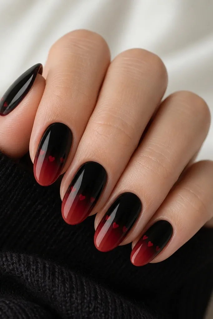 Oval nails; black-to-red ombre fades smoothly, and tiny red micro hearts sit along the transition area near the center of each nail.