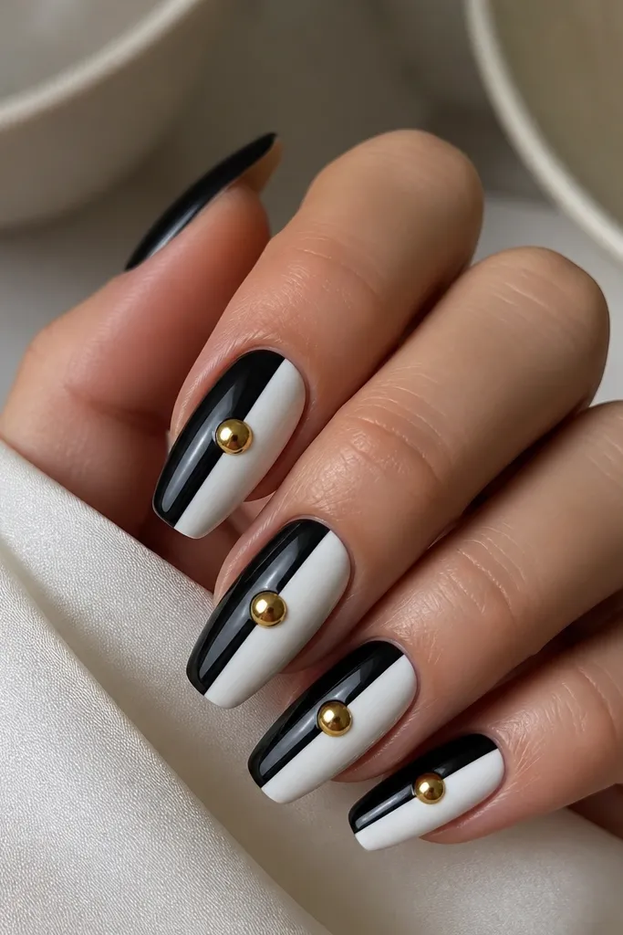 Medium coffin nails split into two vertical halves: one side is black, the other is white. Each side has a half-moon shape near the center with a soft curve. A small gold cap sits exactly in the center.