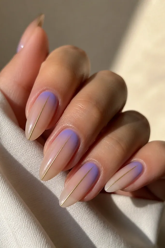 Long almond nails. A periwinkle aura glow spreads around the cuticle in a soft halo. Thin bronze lines run vertically down the center of each nail, stopping before the tip. Base is sheer nude and the overall look is glossy.