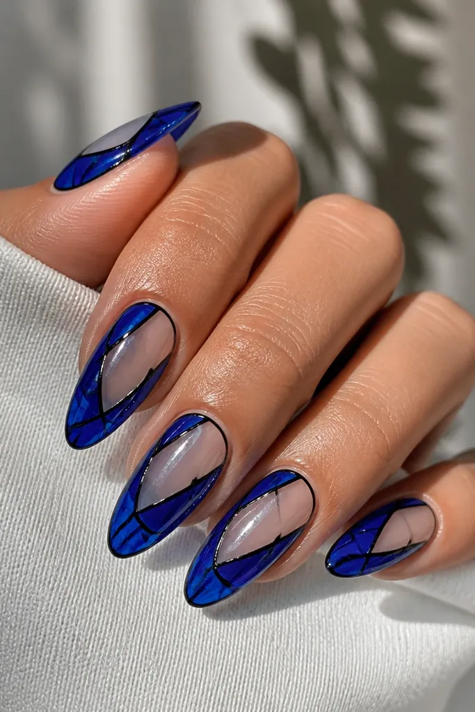 Long almond nails with clear negative panels in the center. Cobalt gel forms stained-glass shapes on the sides, outlined with thin black lines. The overall look is glossy and structured, like window panes.