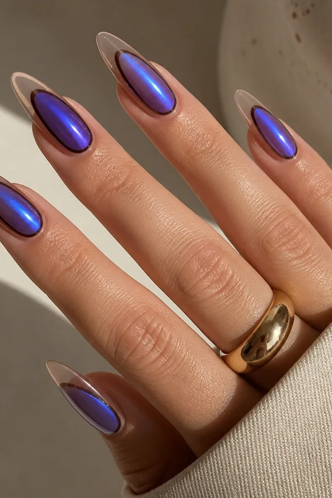 Long almond nails. The center of each nail is coated in blueberry chrome that shifts from blue to purple. Around the chrome sits a thin dark brown outline. The very tip area is kept clear or sheer, creating a negative-space tip.
