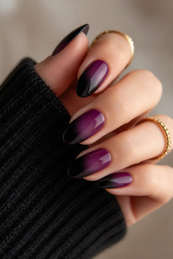 Gradient nails where dark purple fades into black from the tip toward the middle; the transition is smoky with no sharp border, finished with a glossy top coat.
