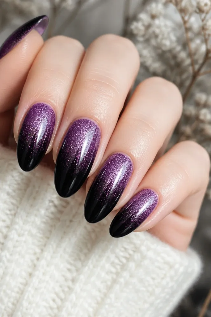Purple glitter fades from mid-nail toward the tip, then black tips take over; glossy top coat smooths the glitter texture.