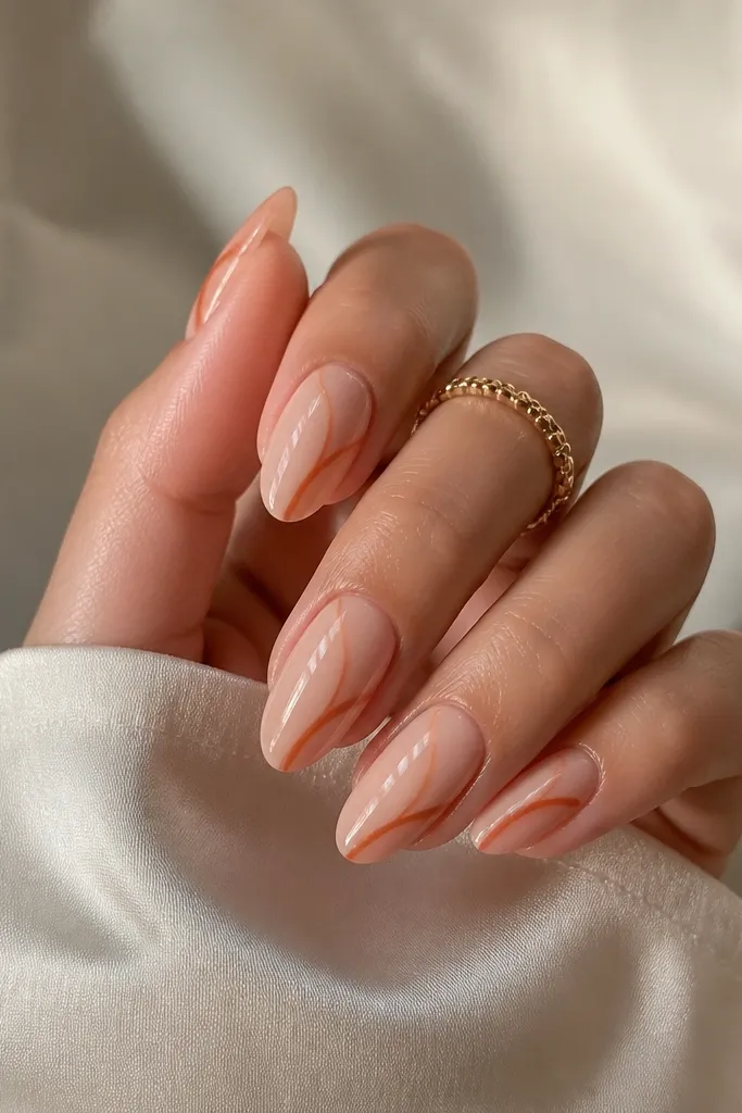 Nude almond nails with a nude base; terracotta half-swirl lines arc from mid-nail toward the side, leaving lots of negative space; glossy top coat.
