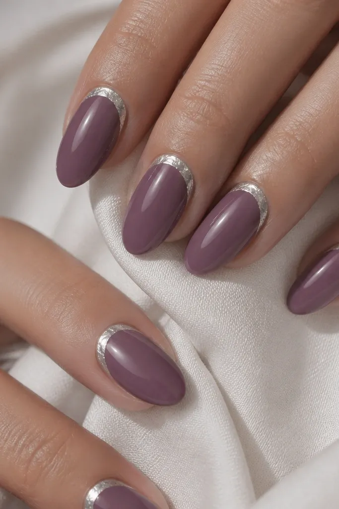 Muted plum almond nails with a silver foil crescent hugging the cuticle on each nail; glossy finish; foil is thin and reflective.