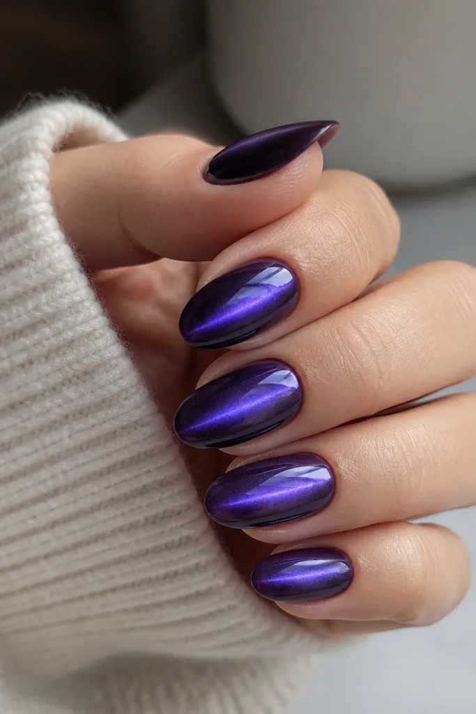 Medium almond nails in deep violet. The cat-eye stripe sits in the center, and around it there's a soft halo glow that looks like a faint ring of light. The top coat is ultra shiny.