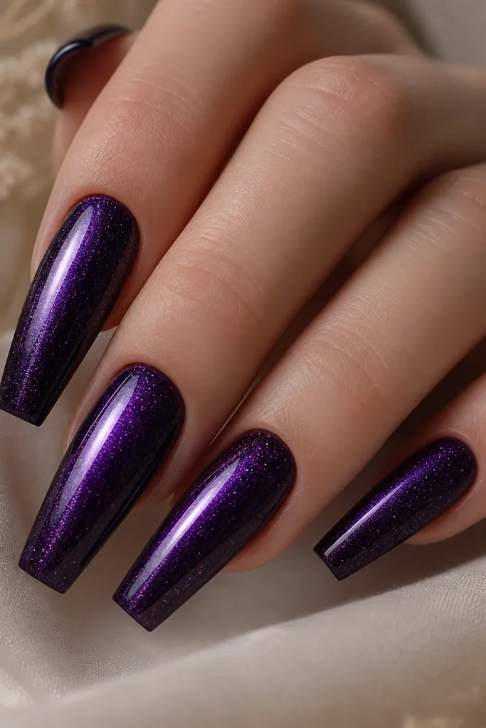 Coffin nails in deep violet purple with a bright center cat-eye stripe. Over the entire nail there's a fine micro-sparkle in the top coat, like tiny silver flecks that catch light but don't look chunky.