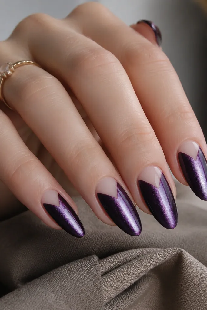 Medium almond nails where the cat-eye stripe runs down the center of a dark purple nail, but the cuticle area is left bare in a sharp V shape. The V creates a clean negative space outline. The rest is glossy and smooth.
