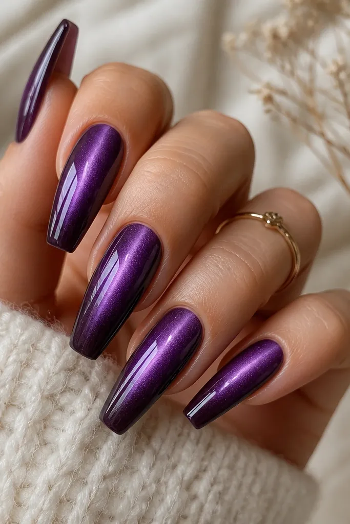 Coffin nails with a medium dark purple base. The cat-eye stripe runs down the center. The tips fade into a slightly darker plum, creating a smooth ombre effect without harsh lines. Glossy finish.