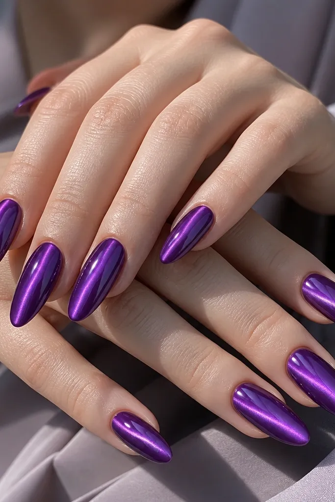 Long almond nails in violet amethyst purple. The cat-eye line is wide and bright, spreading slightly on both sides like a glowing beam. The nails are mirror-gloss with clean cuticles.