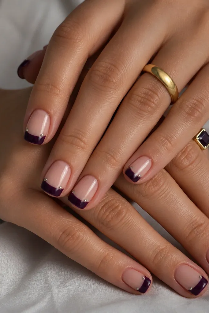 Short square nails with a dark purple French tip. The French line is crisp and wide at the tip. Two tiny silver bead accents sit on each nail on the side near the tip, like miniature studs.