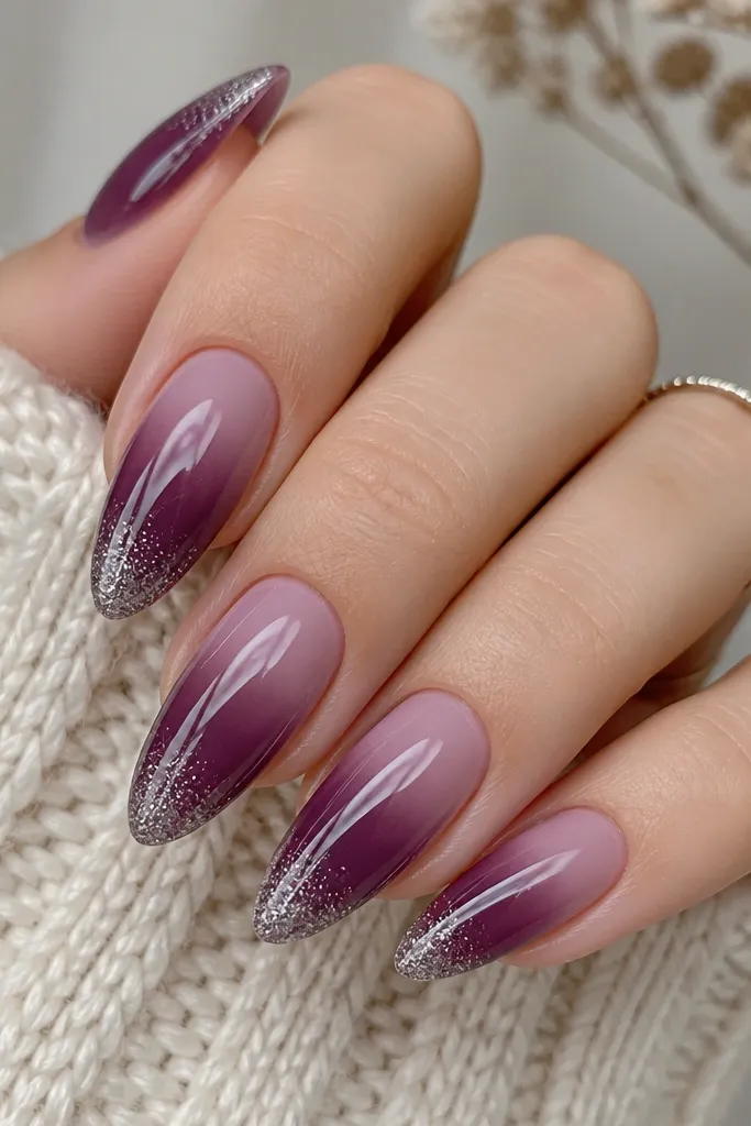 Almond nails with a smooth plum ombré from lighter at the cuticle to deep at the tip. At the very tip, a silver glitter fade cap forms a soft band that blends into the purple.