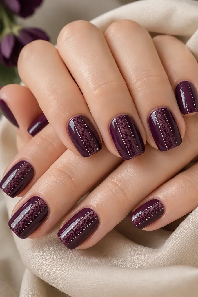 Short-to-medium square nails in dark purple. Near the center, a lace-like pattern appears in a slightly lighter purple, with silver dot borders outlining the lace edges. Glossy finish.