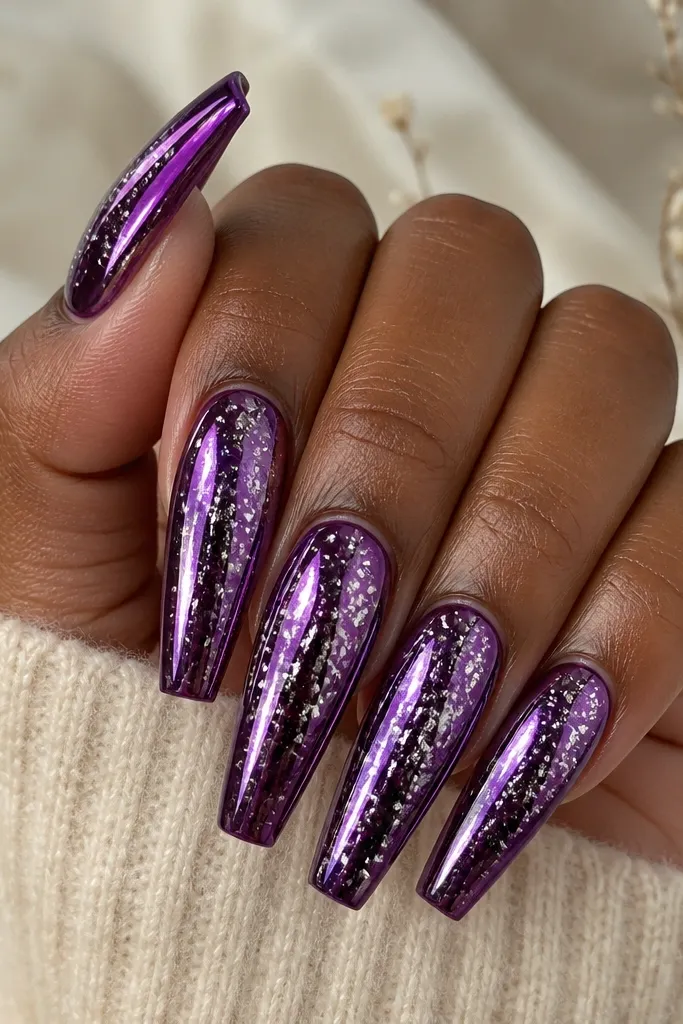 Long coffin nails in deep purple chrome, mirror shine. Random tiny silver foil specks scatter across the nail like confetti, concentrated toward the center and tapering to the edges.