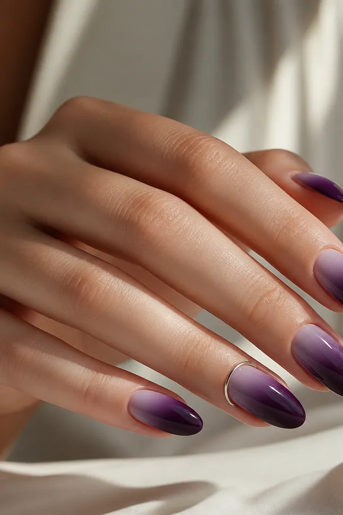 A full set where most nails are dark purple ombré from lighter at the cuticle to deep at the tip. On the ring finger, there's a silver halo ring around the cuticle like a thin bracelet. All nails are glossy.