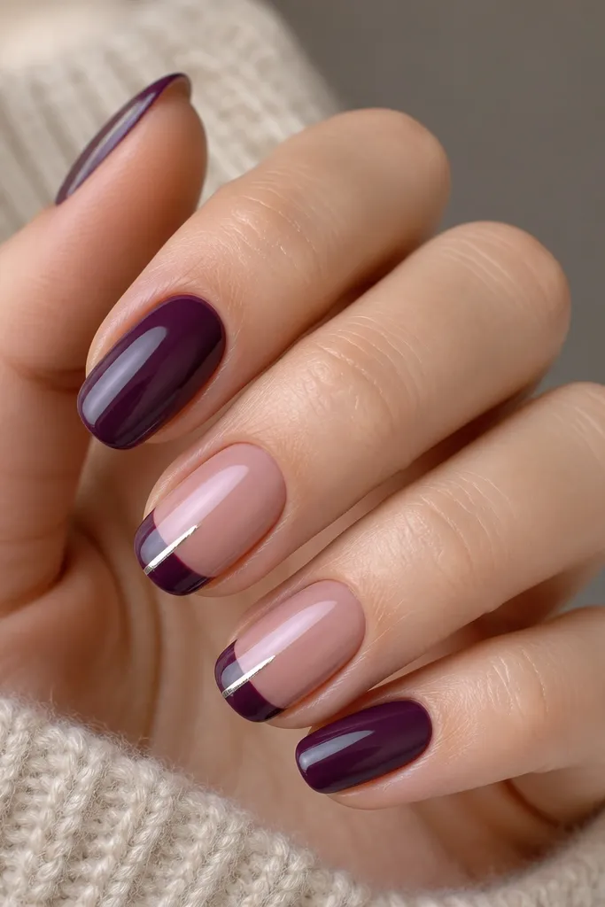 Nails painted solid plum creme. Every other nail has a French tip in deep purple, and there's a thin silver stripe running through the French line like a vertical highlight. Clean cuticles and glossy finish.