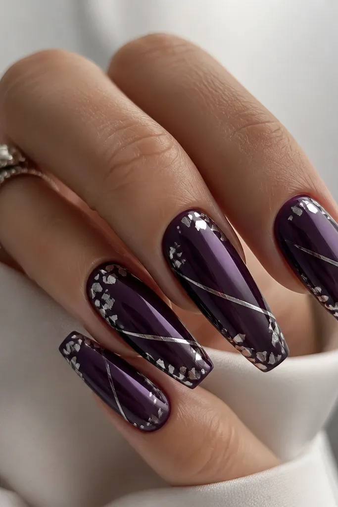 Coffin nails painted dark purple with a glossy, glassy look. Silver confetti pieces sit near the edges, and thin silver "cut lines" run across the nail diagonally like slices of metal. Bright shine, no smudging.