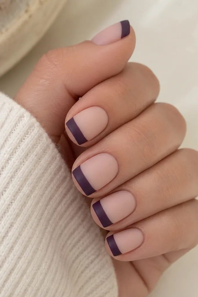 Short square nails with a nude base and matte finish; dark purple French tips are matte and slightly velvety; no shine on tips.