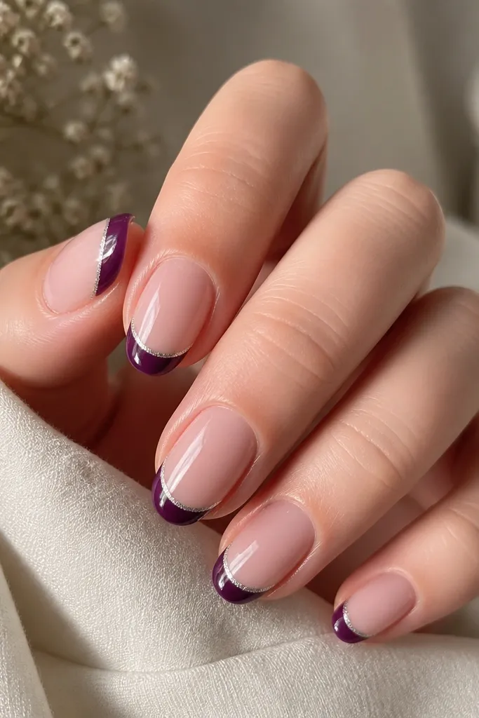 Medium oval nails with sheer rose base; dark purple French tips outlined with a thin silver line along the top edge; glossy finish.