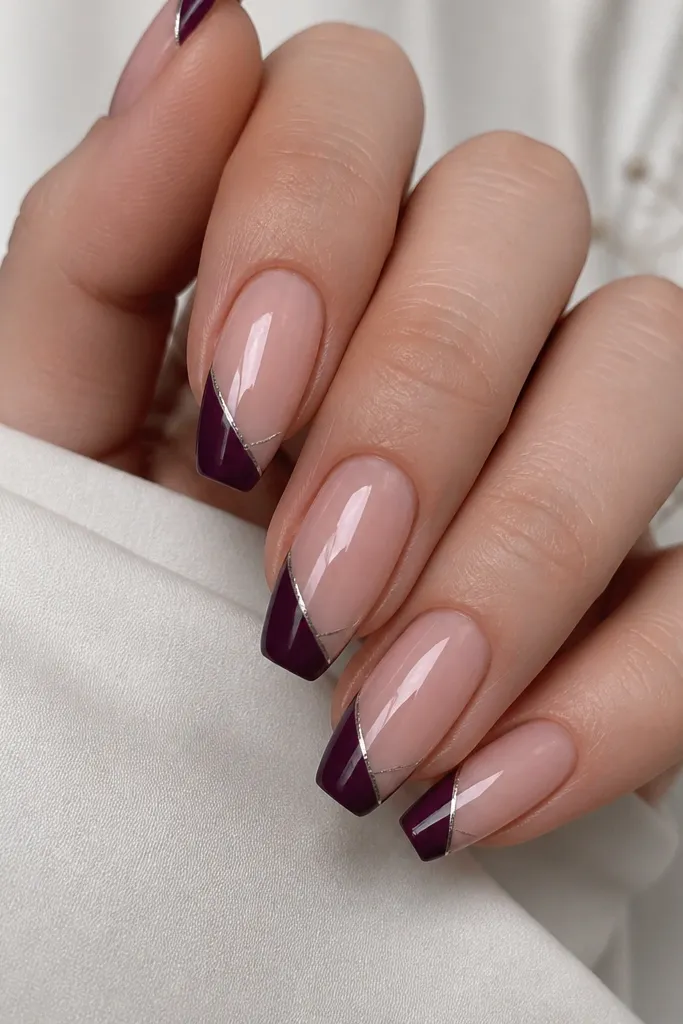 Short coffin nails with nude base; dark grape French tips; one thin diagonal micro stripe in silver running from the tip edge toward the center; glossy finish.